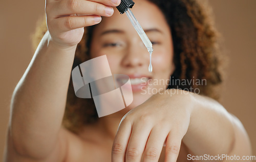 Image of Skincare, product or hands of woman with serum in studio for a natural glow, wellness or cosmetic routine. Bottle closeup, beauty or model with facial oil in dermatology treatment on brown background