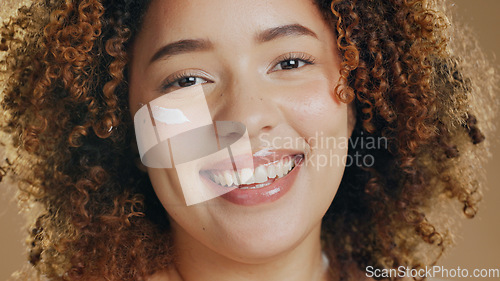 Image of Skincare, black woman and cream on face for dermatology, beauty or happiness on brown background in studio. Skin, care or happy portrait with cosmetics, lotion or sunscreen for wellness or confidence