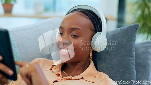 Image of Happy black woman, headphones and relax on sofa with phone listening to music or podcast at home. Face of African female person smile with headset for audio streaming or sound on living room couch