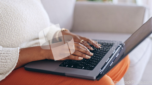 Image of Hands, laptop and a person typing on a sofa in the living room of her home for email communication. Computer, keyboard and an adult typing a social media post or article for her online blog closeup