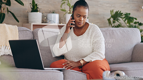 Image of Laptop, phone call and a concerned black woman on a sofa in the living room of her home for problem solving. Computer, communication and worry with a person talking on her mobile for networking