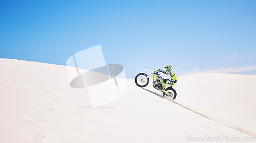 Image of Man, driving and motorbike on sand with blue sky or sport, adventure and outdoor race in summer or mockup space. Motorcycle, ride and athlete on off road, dirt or desert for challenge and danger