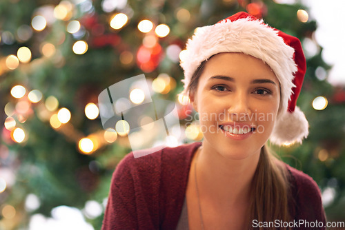 Image of Christmas, woman and happy holiday portrait with cheerful smile at festive tree in home. Christmas tree, happiness and excited girl in home for vacation celebration with red santa hat.