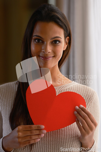 Image of Woman, face and red heart paper in house or home for valentines day, cardiology surgery organ donor or support. Portrait, smile or happy Indian person with love cut out for trust, comfort or kindness