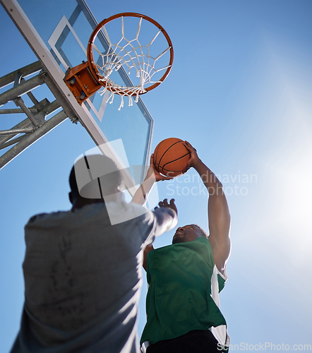 Image of Basketball player, low angle and competition games on blue sky background of outdoor sports, fitness and energy for goals, performance and action. Basketball hoop, friends and men, court and training