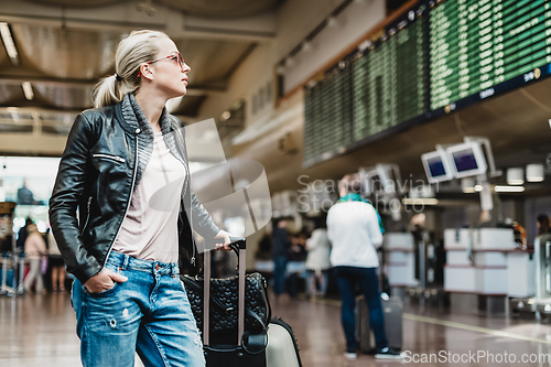 Image of Female traveller checking flight departures board.