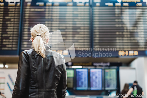 Image of Female traveller checking flight departures board.