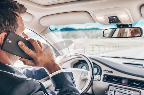 Image of Man using cell phone while driving