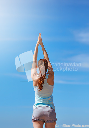 Image of Woman, exercise and yoga for meditation with hands in air against blue sky for freedom, health and wellness outdoor. Fitness model in prayer pose for workout, mindfulness and mental health meditation