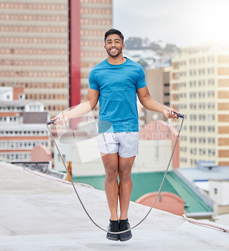 Image of Jump rope, fitness and portrait of a man on a rooftop, sports training and cardio in the urban city. Energy, jumping and athlete skipping for wellness, workout and strong body with happiness