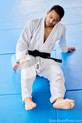 Image of Sports, injury and pain in legs on karate fitness dojo floor for tournament, training or workout. Professional athlete uniform of martial arts man with knee pain or arthritis at sport club.