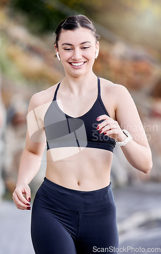 Image of Runner, fitness and woman running outdoor, wireless earphones for music or podcast and happy with workout. Run, active and healthy lifestyle, wellness in nature and listening for training motivation