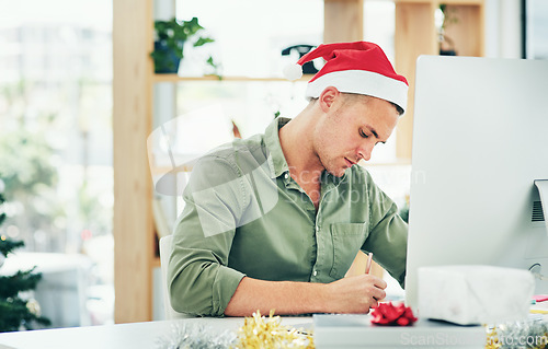 Image of Christmas, computer and businessman writing at a desk, thinking and planning in his office alone. Festive, season and employee working to meet deadline on xmas eve, write list, note or reminder