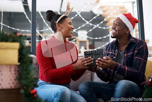 Image of Gift, couple and christmas celebration on sofa by happy, excited and loving people sharing joy, cheer and giving in their home. black couple, box and gift exchange in a living room, festive and xmas