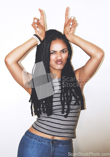 Image of Portrait, hand gesture and horns with a black woman posing in studio on a gray background for quirky fun. Face, fashion and beauty with an attractive young female making a devil horn sign with hands