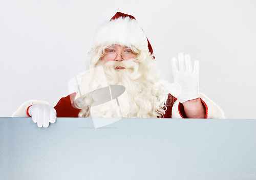 Image of Christmas, santa and portrait with hand wave for friendly festive holiday greeting advertising. Celebration, vacation and santa claus man waving hello with white studio marketing mockup background.