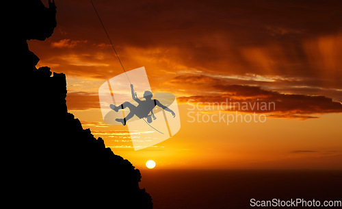 Image of Sunset sky abseiling, mountain silhouette and hiking man hanging on shadow rope. Fitness risk, adventure freedom challenge and strong, surreal nature adrenaline and cliff climbing on orange landscape