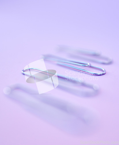 Image of Row, paper clips and office stationery for paperwork in a studio with a purple background. Work supplies, equipment and steel wire clips in a line to organize or hold document, report or form sheets.