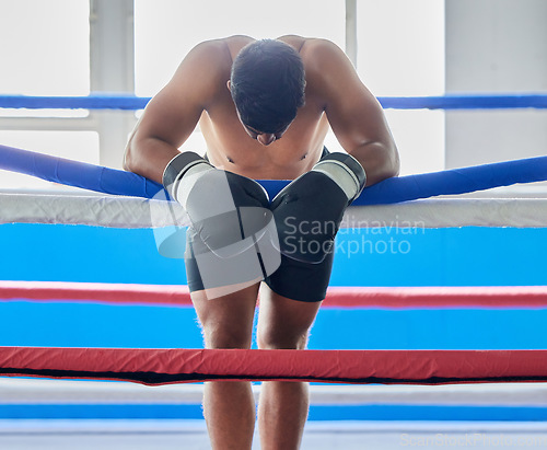 Image of Fitness, tired and sad boxer after a loss thinking about his defeat in a difficult battle in a boxing ring at a gym studio. Fatigue, loser and frustrated fighter feeling bad, depression and upset