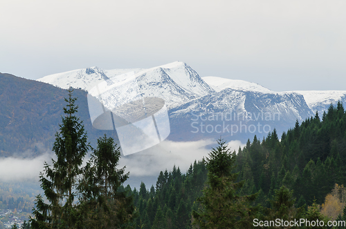 Image of snow-capped mountain peaks above mist-covered valleys