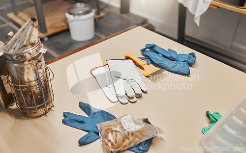 Image of Beekeeping, bee bellows and gloves in workshop for safety, equipment or farming at apiary job. Beekeeper factory, ppe or plant for preparation, industry or warehouse in workplace at apiculture farm