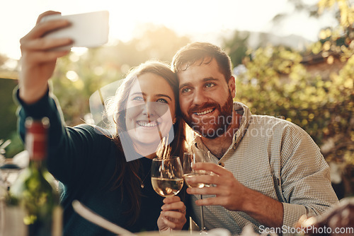 Image of Wine, phone and couple take a selfie with a toast to a happy marriage and share romantic content on social media. Woman smiles taking pictures on a date with a lovely partner drinking champagne