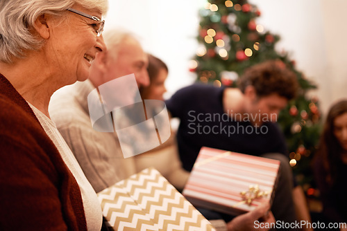 Image of Christmas, gift and happy with family in living room for celebration, festive and holiday. Smile, party and gratitude with old woman and present with children at home for giving, event and tradition