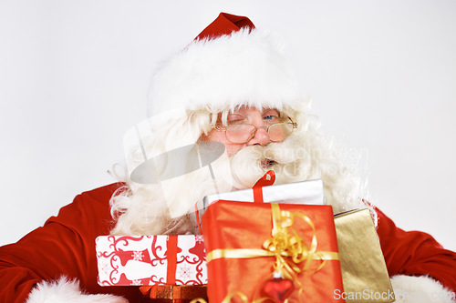 Image of Christmas, santa and gift portrait with wink for traditional festive holiday advertising. Present, giving and santa claus man with colorful ribbon boxes on white studio mockup marketing.