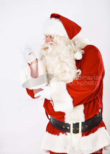 Image of Father Christmas in studio pointing to white background for marketing, branding or advertising mockup space. Product placement, santa claus or old man shows retail sales discount offer or promo deal