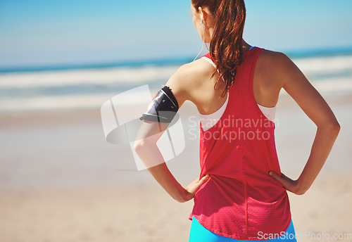 Image of Beach, fitness and woman athlete by the sea looking at ocean back view before running workout. Health, wellness and freedom feeling outdoor in summer for exercise, sports and headphones with music