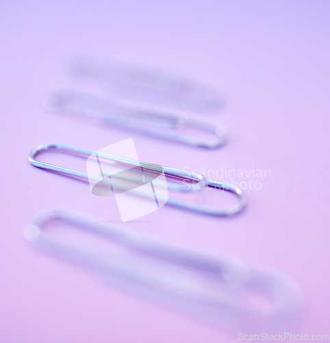 Image of Paperclip, filing and organization for documenting or attachment in studio on a purple background. Business, office and stationery with a metal clip for file or storage purposed on a color surface