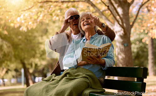 Image of Park, bench and binoculars with a senior couple birdwatching together outdoor in nature during summer. Spring, love and book with a mature man and woman bonding while sitting in a garden for the view