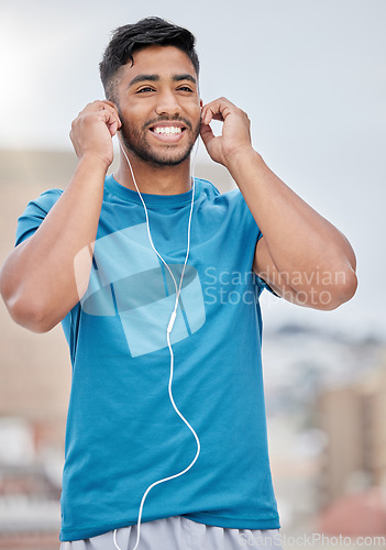 Image of Man, music and earphones for city exercise for wellness, training and running by blurred background. Happy runner, listening and streaming on internet, web or app to relax at workout in urban metro