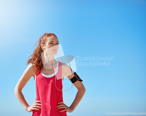 Image of Runner woman, outdoor and sky with earphones for music, workout motivation and training in summer. Young athlete girl, exercise and running for wellness by blue sky with focus, sunshine and fitness