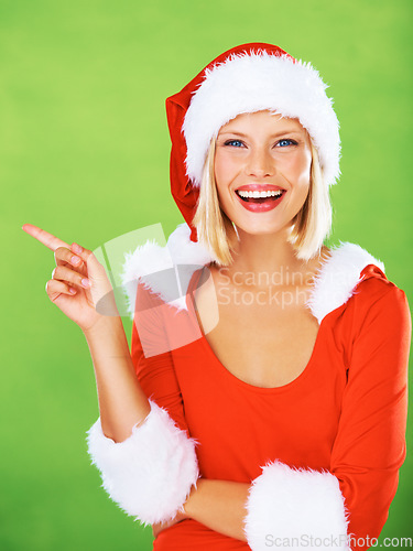 Image of Portrait and woman in santa costume pointing for marketing or advertising space on a green studio background. Xmas, festive season and woman with hand gesture and mockup space on a background