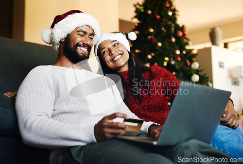 Image of Christmas, couple and couch with laptop, credit card and together for finance, festive season and ecommerce in lounge. Xmas, man and woman for payment, investments and online banking for transactions