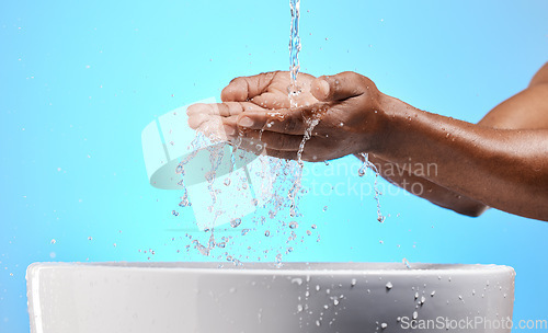 Image of Cleaning, washing and hands with water in studio on blue background for wellness, hydration and virus safety. Skincare, health and black person washing hands for germ protection, hygiene and bacteria