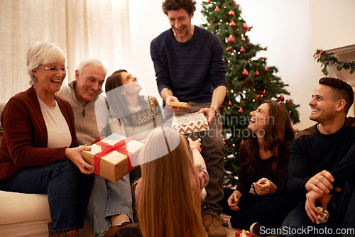 Image of Christmas, happy and gift with family in living room for for celebration, holiday and festive gratitude. Relax, smile and present with parents giving box to children at home for content on xmas party