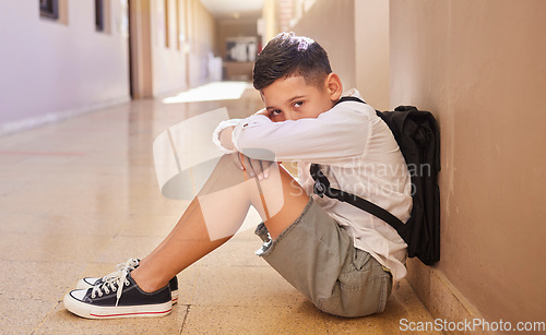 Image of School child, bullying and sad student on ground for depression, anxiety and autism or learning problem in hallway. Boy feeling stress and depressed after abuse, violence or discrimination portrait