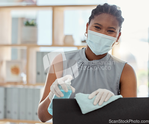 Image of Covid, mask and sanitizer with a business black woman cleaning her computer and office equipment at work. Portrait, sanitizing and wipe with a female employee during the corona virus pandemic