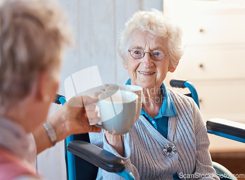 Image of Senior woman, happy friends and toast coffee in wheelchair in room, house or nursing home together. Elderly women, mug and smile for love, bonding and care in home with disability with happiness