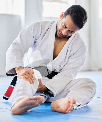 Image of Injury, karate and man with knee pain after an accident in martial arts training in a wellness studio or dojo. Fitness, taekwondo and fighter with leg pain, emergency or joint pain after a workout