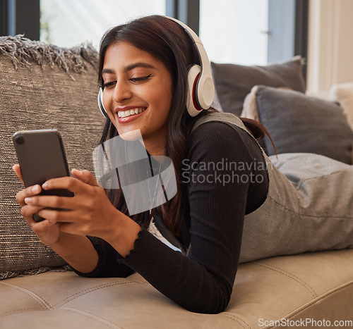 Image of Woman, phone and headphones for listening to music online for happiness, calm and peace while streaming on audio app on home and living room sofa. Female watching video or movie on internet with 5g