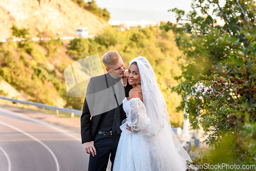 Image of Happy newlyweds are hugging against the backdrop of a beautiful mountain landscape, the girl looked into the frame with a wide smile