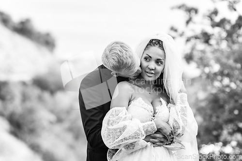 Image of Happy newlyweds hugging against the backdrop of a beautiful mountain landscape, a guy kissing a girl, black and white version