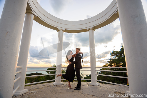 Image of A young couple hugs in a gazebo against the backdrop of a beautiful landscape