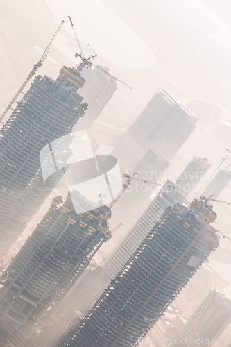 Image of Skyscrappers construction site with cranes on top of buildings.