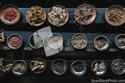 Image of Various spices displaied on small ceramic and metal plates on black wooden background.