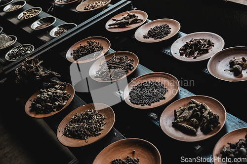 Image of Various spices displaied on small ceramic and metal plates on black wooden background.