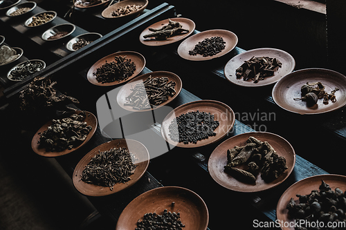 Image of Various spices displaied on small ceramic and metal plates on black wooden background.